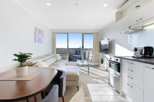 a kitchen and living room with a table and a couch at City Vista Apt with Views - Pool and Gym in Auckland