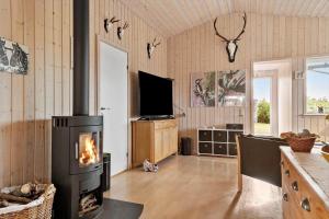 een woonkamer met een open haard en een televisie bij LN2032-Hjorring-Krattet-9 in Lønstrup