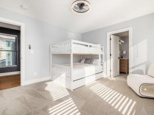 a white bedroom with a bunk bed and a chair at High End New Build, Rooftop Hot Tub, City Views in Milo