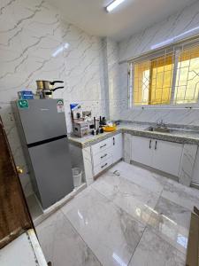 a white kitchen with a refrigerator in the middle at Grand Mombasa Apartments in Mombasa +22 photos
