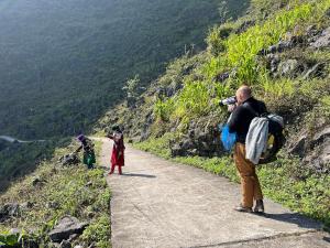 a man taking a picture of two people on a mountain path at Mèo Vạc Giấc Xưa Homestay in Mèo Vạc