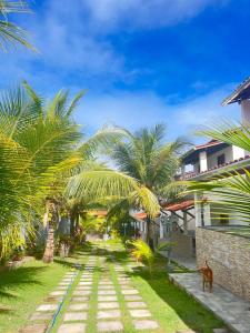 a pathway with palm trees in front of a building at Residencial Jardim Imbassai 4 apt mobiliado com piscina in Mata de Sao Joao