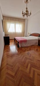 a bedroom with a bed and a wooden floor at Habitación en A Coruña con baño privado in Visma