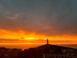 a lighthouse on top of a hill with a sunset at Habitación en A Coruña con baño privado in Visma