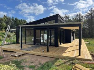 een klein zwart huis op een houten terras bij JB365-Fjerritslev-Hedestien-9 in Torup Strand