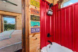 a bathroom with a red wall with signs on it at Hill Country Cabin - Cozy Rustic Getaway in Fredericksburg