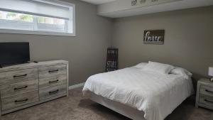 a bedroom with a bed and a dresser with a television at Oasis at Heritage in Fort McMurray