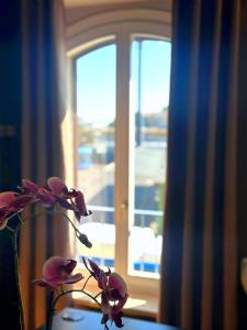 a vase with flowers in front of a window at Appartamento Cremona Stazione in Cremona