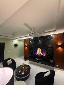 un salon avec une télévision à écran plat sur un mur dans l'établissement Zameen Opel, à Lahore 2 autres photos