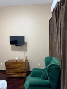 a living room with a green chair and a tv at House of Peace in Fombeni