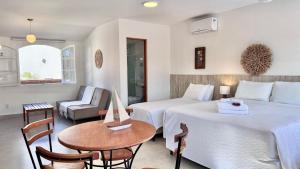 a hotel room with two beds and a table at Bella Buzios Apartamentos in Búzios