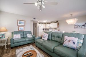 a living room with two green couches and a kitchen at Fenimore Mill 1A Mermaid's Song in Cedar Key