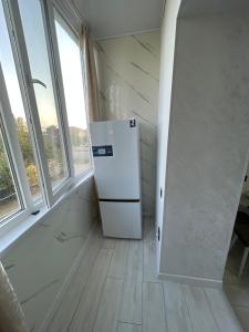 a white refrigerator in a room with windows at Чистая квартира для добрых людей in Bosteri