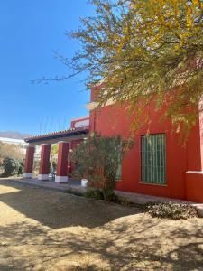 czerwony budynek z drzewem przed nim w obiekcie Casa de Campo w mieście Cafayate