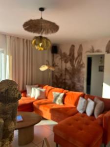 a living room with orange couches and a chandelier at Maison Margot Villa provençale a 300m de la plage in Cavalaire-sur-Mer