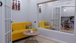 a living room with a yellow couch and a table at Comfort City 3-Room Apartments in Almaty