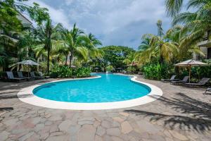 a swimming pool in a resort with palm trees at Pacifico L302 in Coco