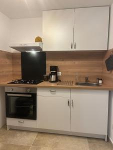 una cucina con mobili bianchi e un forno a piano cottura di Charmant Studio village montagne a Bastelica