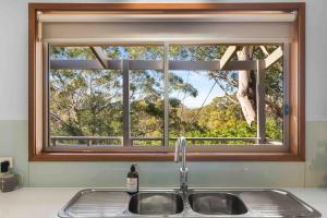 a kitchen sink with a window above a kitchen counter at Blenheim Hideaway by Experience Jervis Bay in Vincentia +17 photos