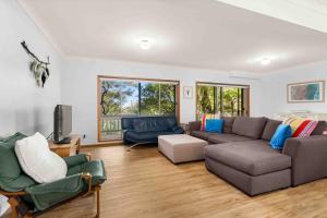 a living room with a couch and a tv at Blenheim Hideaway by Experience Jervis Bay in Vincentia
