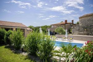 una piscina in un cortile con sedie e ombrelloni di Villa Mendula in Čambarelići - Haus für 6-7 Personen a Kršan