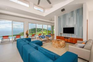 a living room with a blue couch and a tv at Casa Tres Vistas Bonitas 4br New! Modern Villa in Playa Hermosa
