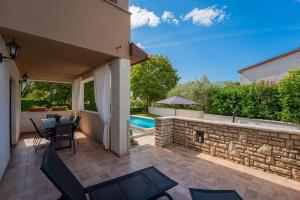 a patio with a table and chairs and a swimming pool at Villa Rita in Pinezići - Haus für 5 Personen in Marčana