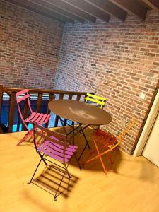 a table and four chairs sitting next to a brick wall at La Ferme des Roses in Tournai