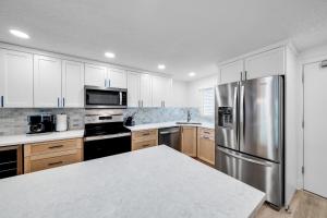 Una cocina con gabinetes blancos y un refrigerador de acero inoxidable. en Fully renovated direct oceanfront condo with a large balcony, heated pool and beach access, en Bottle Island