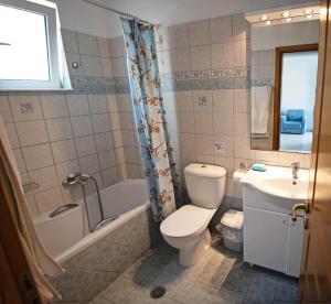 a bathroom with a toilet and a tub and a sink at Nephele Apartments in Faliraki