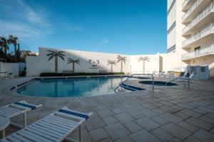 Una piscina con tumbonas y un edificio. en Stunning direct oceanfront condo with a balcony, hot tub, and heated pool, en Bottle Island