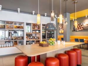a restaurant with a table and red stools at B&B Hotel Stuttgart-Zuffenhausen in Stuttgart