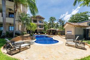 a swimming pool with two chairs and a building at Sol Y Mar 4c in Playa Hermosa