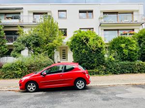 ein rotes Auto, das vor einem Gebäude geparkt ist in der Unterkunft Ruhiges Messezimmer im Diplomatenviertel mit Grünblick in Niederdorla