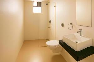a bathroom with a white toilet and a sink at LUXY Service Apartment at North GOA in Calangute +6 photos