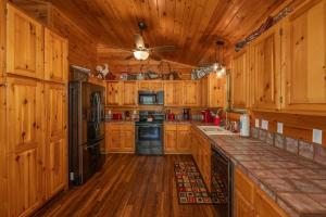 a kitchen with wooden cabinets and a black refrigerator at Hawks Heart Lodge by American Patriot Getaways in Shady Grove