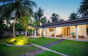 a house with a yard with palm trees at Villa Lihiniya in Unawatuna