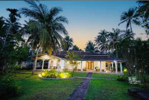 a house with palm trees in front of a yard at Villa Lihiniya in Unawatuna