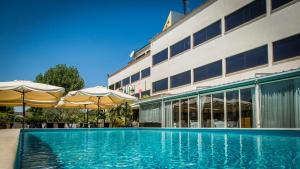 a swimming pool in front of a hotel with umbrellas at Hotel Cristallo Relais, Sure Hotel Collection By Best Western in Tivoli