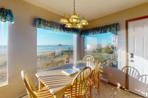 una sala da pranzo con tavolo e sedie e una grande finestra di Ocean Vista Cottage a Bandon