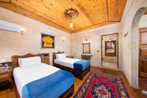 een slaapkamer met twee bedden en een houten plafond bij Aja Cappadocia Cave Hotel in Urgup
