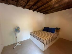 a bedroom with a bed with blue pillows and a fan at The Grove 1-4 bedroom beachfront villa in Cap Skirring