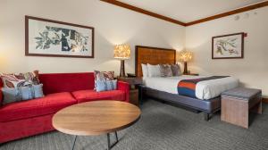 une chambre d'hôtel avec un lit et un canapé rouge dans l'établissement 323 Studio Spruce Peak Lodge At Stowe Mt Resort Sleeps 4, à Stowe Mountain