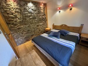 una camera da letto con un letto e un muro di pietra di Domaine de la prairie des prés a Vagney