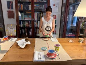 a woman standing at a table with cups and plates at Museo Grillo Camere d'Arte, dormire nel Museo in Arena Po