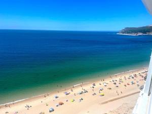 a group of people on a beach with umbrellas at Estrela do Mar - Ocean View Apartment - Sesimbra - Falésia in Sesimbra