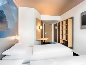 维林根B&B Hotel Willingen的带电视的客房内的2张白色床