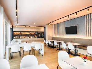 a restaurant with white chairs and tables and a tv at B&B Hotel Willingen in Willingen