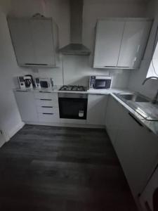 a kitchen with white cabinets and a stove and a sink at 3 Bed Semi, Bingley, BD16, Free Parking, Wi-Fi in Bingley