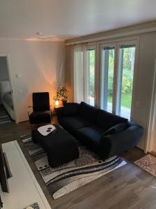 タンペレにあるMatilda Apartment with Peaceful environment and Barbecue facilitiesのリビングルーム(黒いソファ、椅子付)
